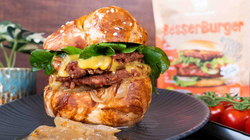 Veganer Smashed Burger mit karamelisierten Zwiebeln im Laugenbrötchen